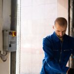Caucasian male technician working indoors with PPE in industrial setting.